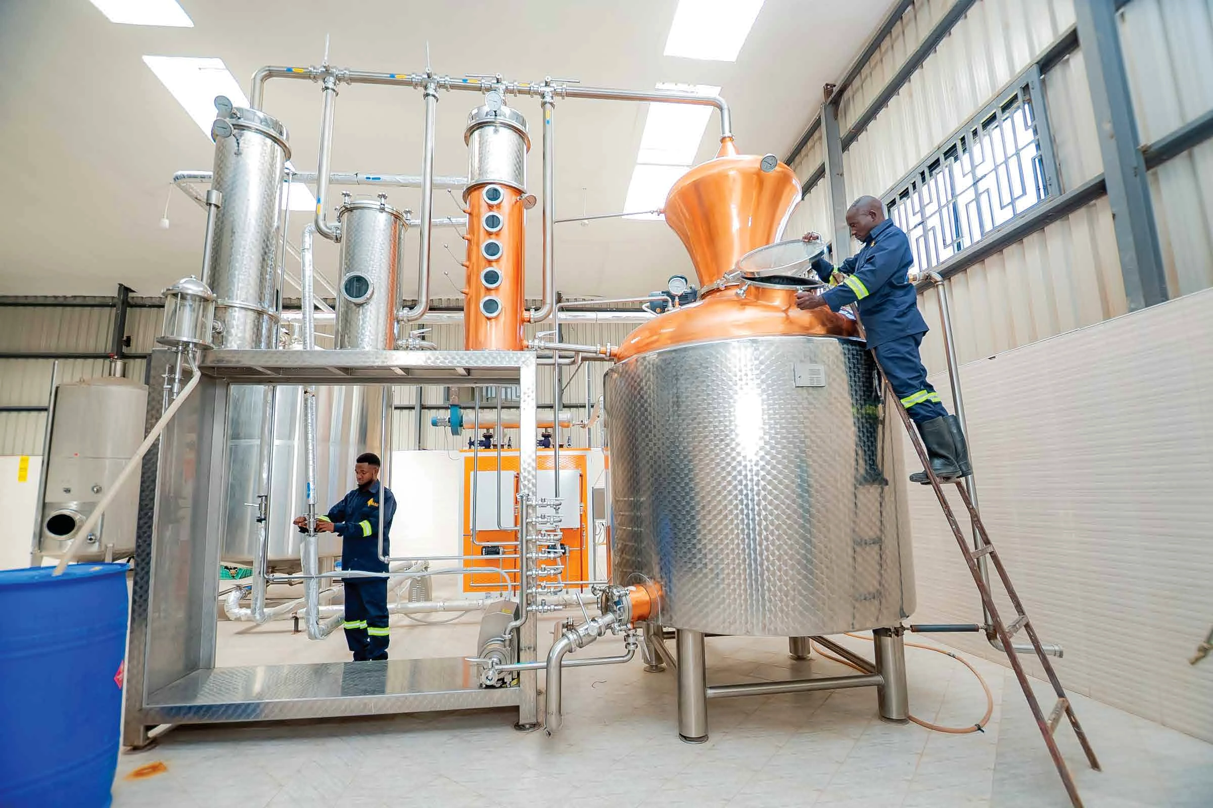 Alko production specialists operating stainless steel distillation equipment